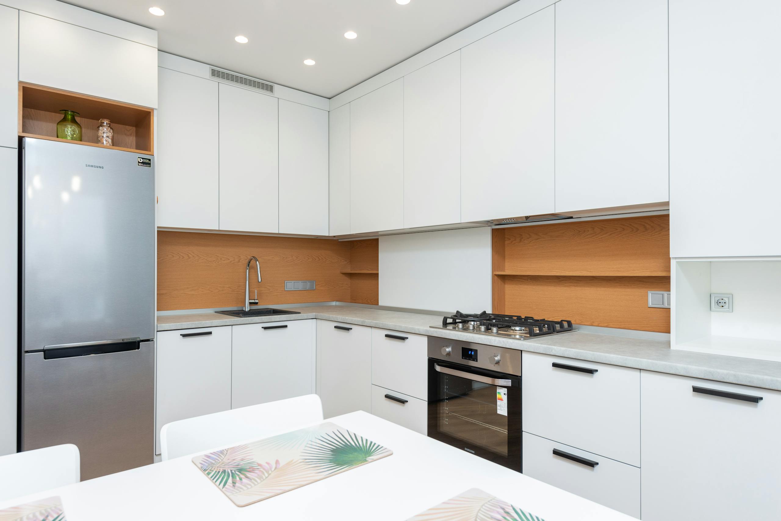 Interior of modern simple kitchen with white furniture and expensive equipment in daytime