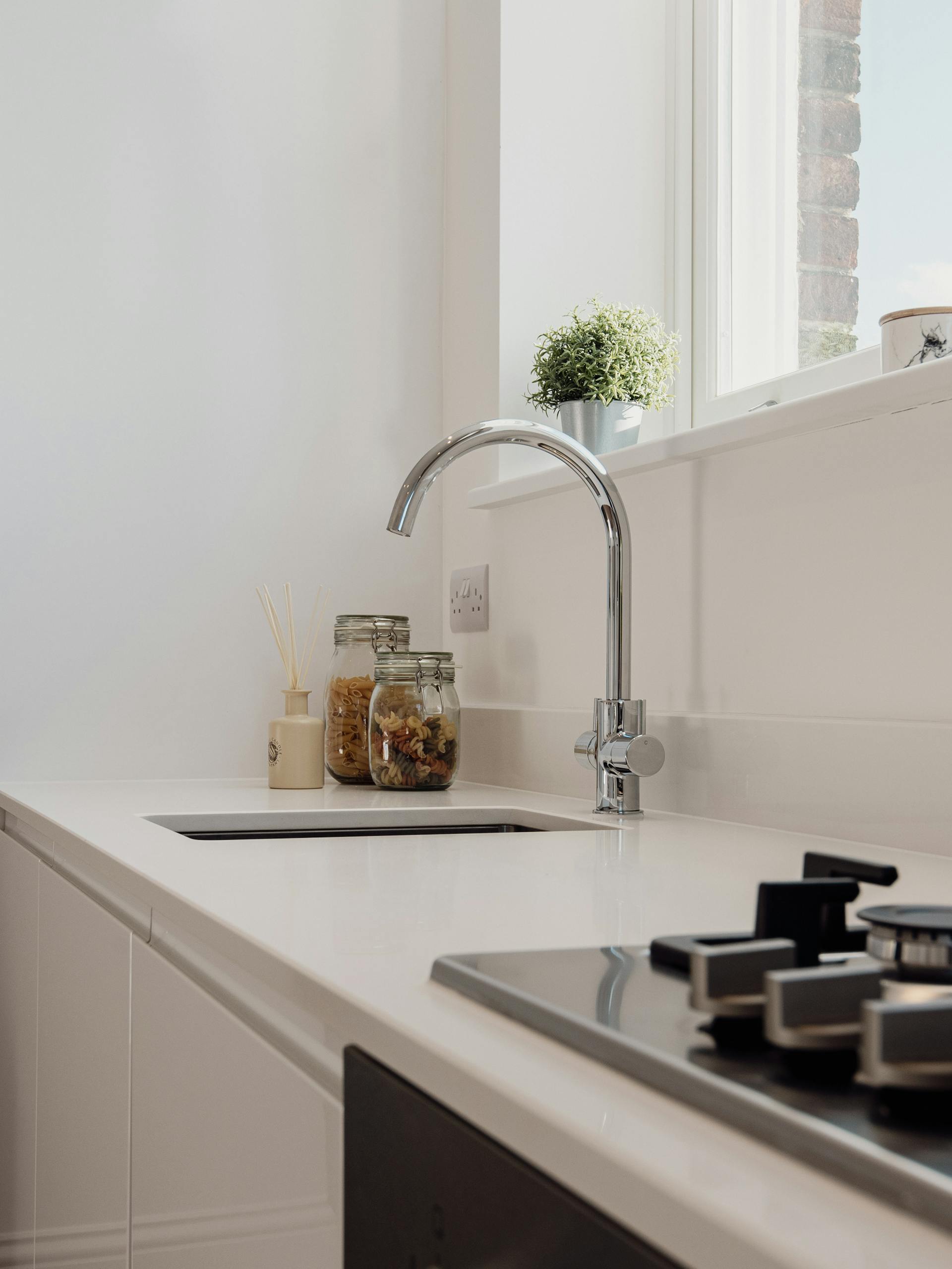 Elegant kitchen featuring minimalist white decor with jars and a gas stove.